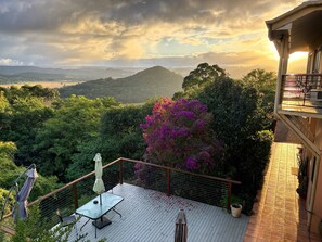 A balcony with a table and chairs, overlooking a lush landscape and distant hills. - RiverRock Retreat Maroochy, Sunshine Coast: 6 bed 6, bath, 15 min from beach (Maroochy river)