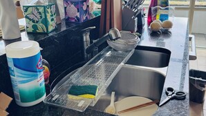 Een keuken met een RVS spoelbak, een snijplank, een spons en een fles afwasmiddel.
