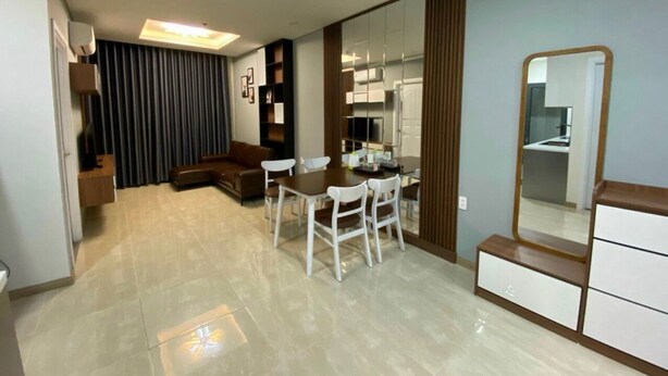 A modern living room with a dining area, a sofa, a coffee table, and a large mirror. - Le Indochina Hotel by AHH Group (Da Nang)