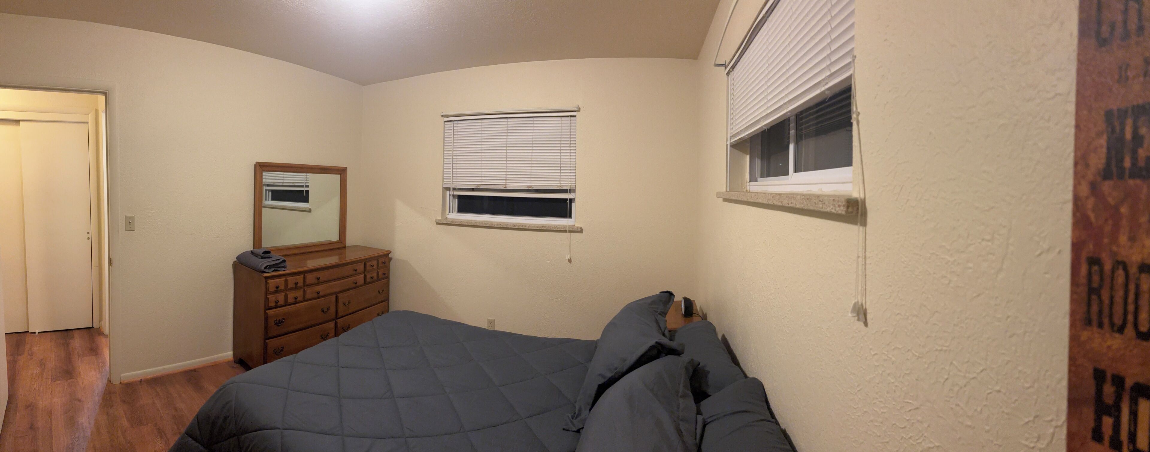 A bedroom with a bed, dresser, and a window with blinds.