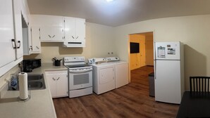 A compact kitchen with white cabinets, a stove, a microwave, and a refrigerator.