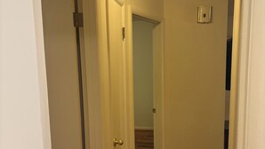 A narrow hallway with white doors and a wooden floor.