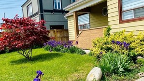 A residential house with a well-maintained garden, a visible water tank on the roof, and a clear sky. - Three Bedroom Bungalow with free parking, closer to commercial area and highway (Mississauga)