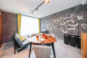 Una habitación moderna con una mesa redonda, sillas, un sofá y un amplio mural abstracto en la pared.