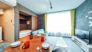 Une chambre d’hôtel moderne équipée d’une table à manger, d’un téléviseur, d’un canapé et d’une fenêtre avec des rideaux.