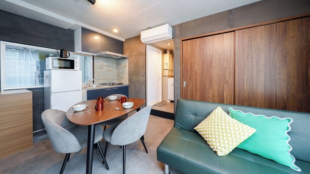 Une cuisine moderne avec un coin repas, un canapé agrémenté de coussins à motifs et une armoire en bois.