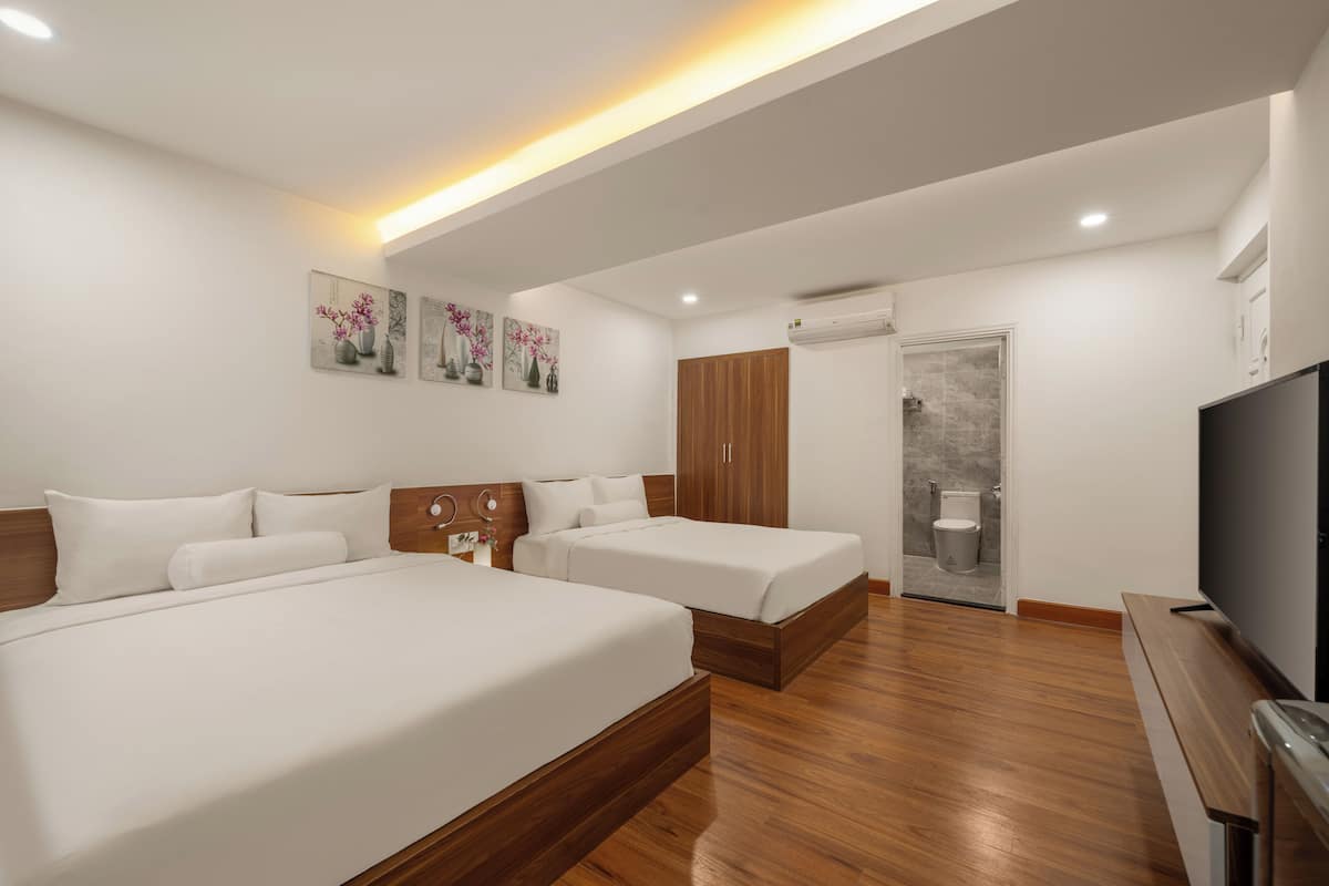 A modern hotel room with two beds, a TV, and artwork on the wall.