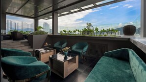 Ein modernes Interieur mit Glastrennwand, sits Möbeln in Türkis und Blick auf die Stadtlandschaft.