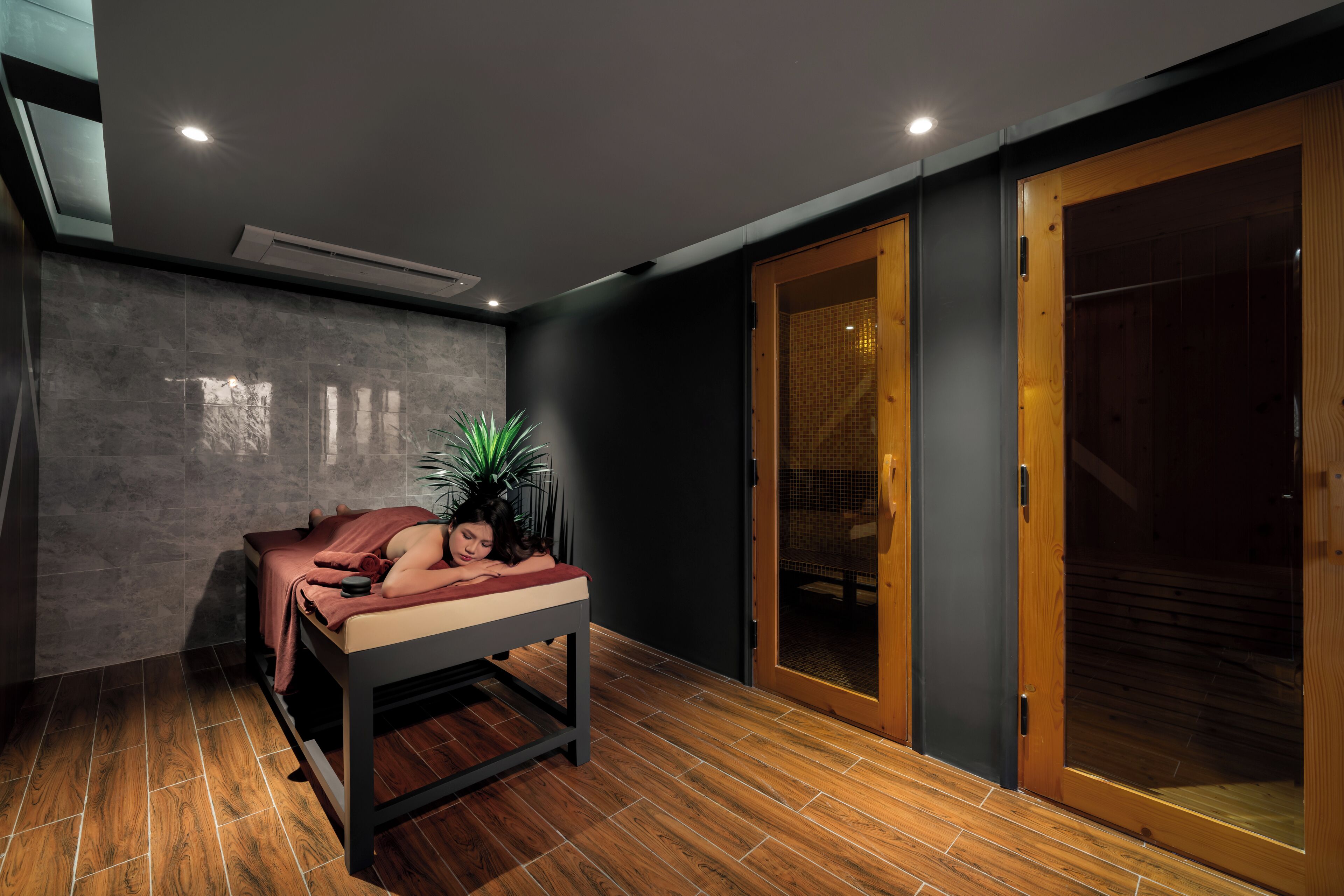 A room with a massage table, a potted plant, and a sliding glass door.