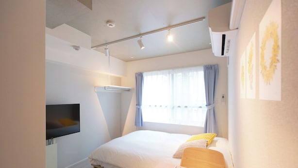 A modern hotel room with a bed, a TV, a dining table with breakfast items, and a window with curtains. - Bellie Sangenjaya by Tranova (Tokyo)