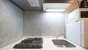 A kitchen with a gas stove, a sink, and a microwave. - Bellie Sangenjaya by Tranova (Tokyo)