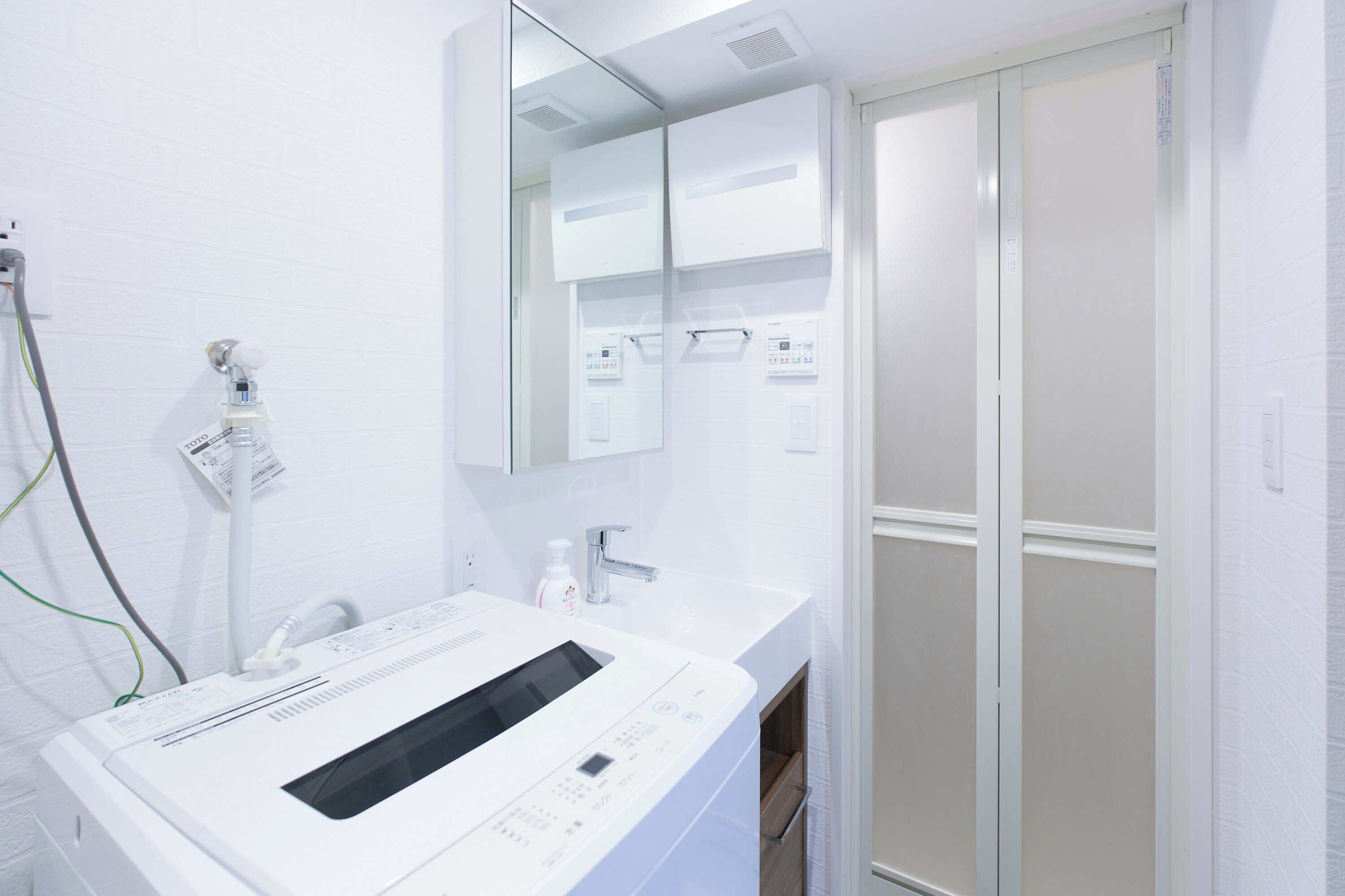 A modern bathroom with a white sink, a mirror, and a shower enclosure.