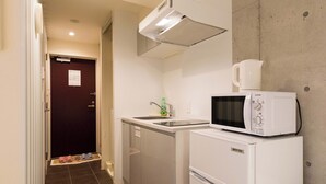 A compact hotel room with a kitchenette, a bed, and a bathroom.