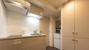 A modern kitchen with a built-in dishwasher, a sink, and a microwave. There are cabinets and a countertop with a sign indicating the location of the escape route.