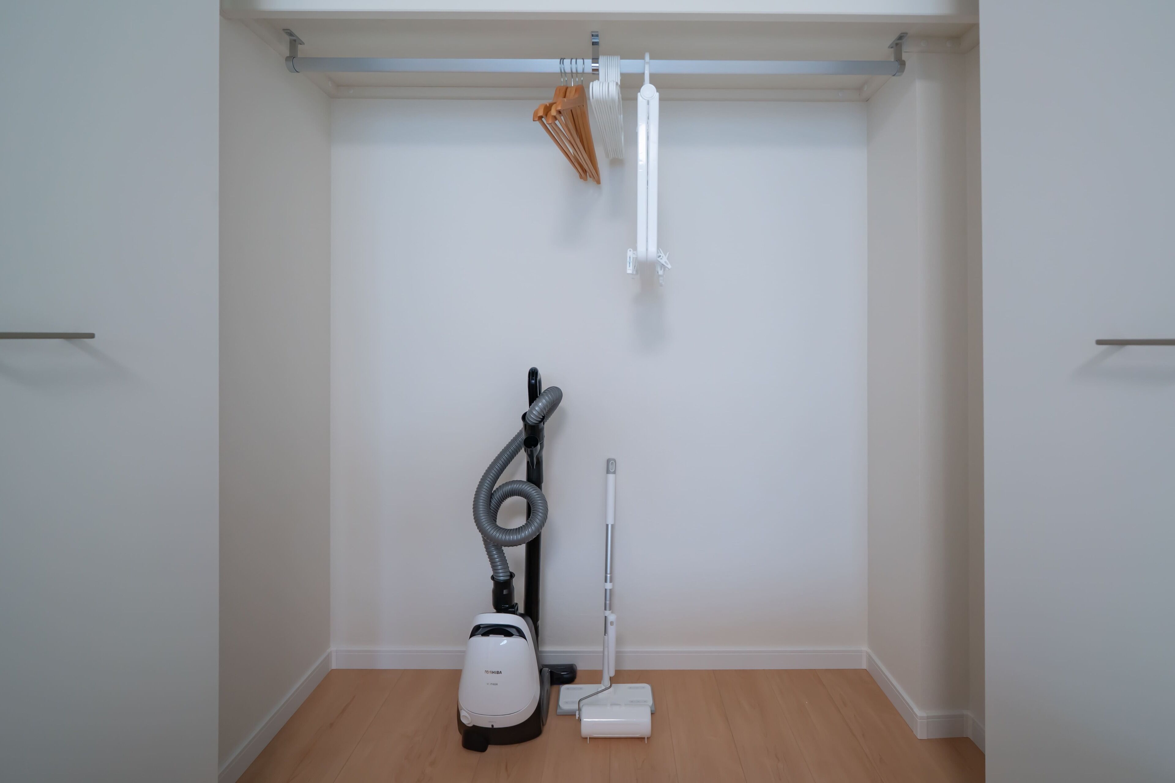 Ein Zimmer mit Staubsauger, Mopp und einer Kleiderstange.