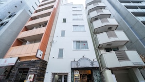 A multi-story building with a restaurant on the ground floor, featuring a sign with Japanese characters and a phone number. - Yamamoto Building by Tranova (Tokyo)