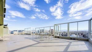 Une terrasse sur le toit offrant une vue dégagée sur le paysage urbain, aménagée avec des tables et des chaises.