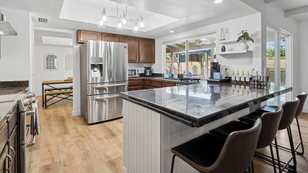 Een moderne keuken met een groot eiland, roestvrijstalen apparatuur en een bar.