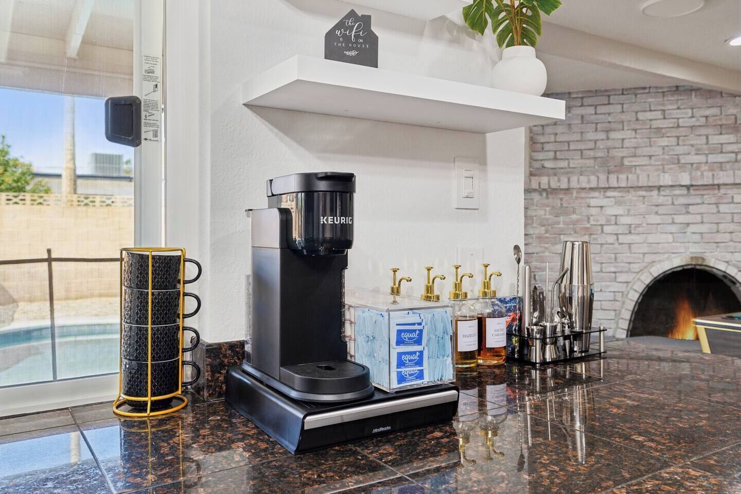 A modern kitchen with a Keurig coffee maker, a coffee station, and a brick fireplace.