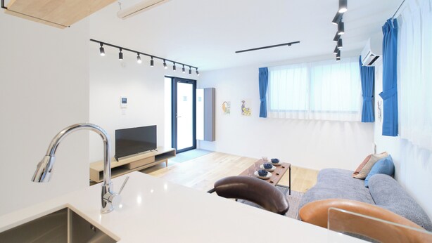 A modern apartment with a kitchen, dining area, and living room. It features a large window with curtains, a flat-screen TV, and a sofa. - Grand Maison Natsumesaka by Tranova (Tokyo)