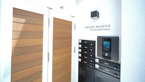 A hotel entrance with a wooden door, a mailbox, and a wall-mounted security camera. - Grand Maison Natsumesaka by Tranova (Tokyo)