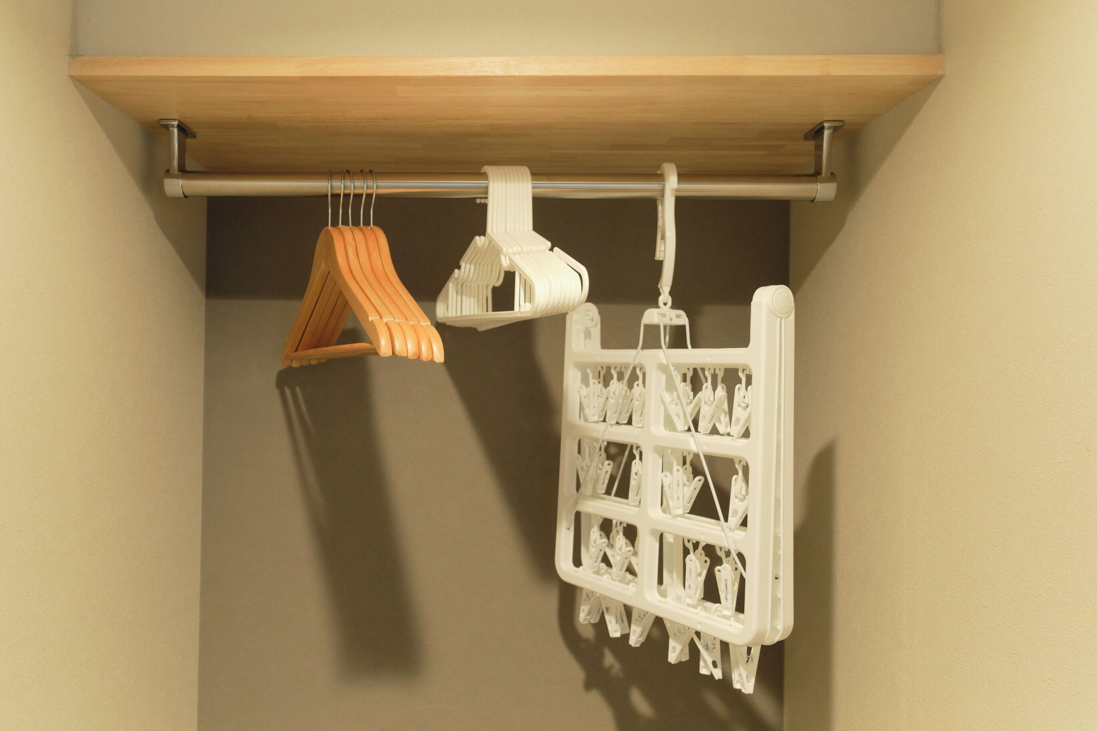 A wooden shelf with a white hanging rack and a white plastic drying rack.