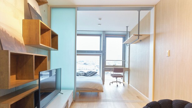Ein modernes Schlafzimmer mit Bett, Fernseher und Schreibtisch.