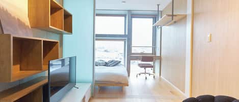 Un dormitorio moderno con cama, televisión y zona de escritorio.