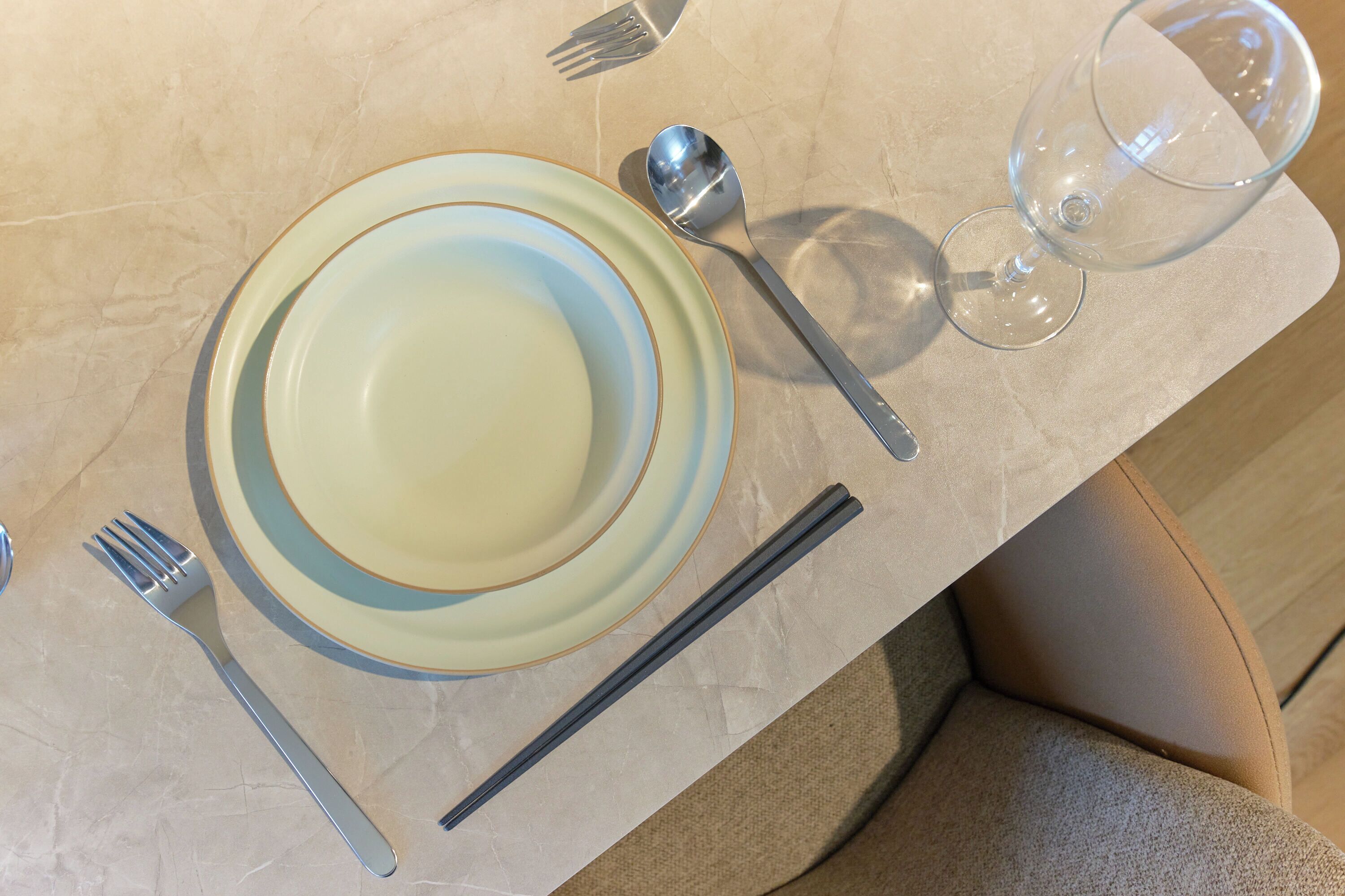 Una mesa dispuesta con platos, cubiertos y una copa.