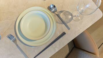 Una mesa dispuesta con platos, cubiertos y una copa.