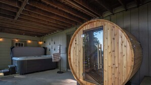 A hot tub and a wooden barrel structure with a glass door.