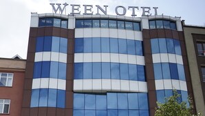 A modern hotel with a reflective glass facade, a prominent sign at the top, and a flagpole with a flag. - WEEN OTEL (Trabzon)