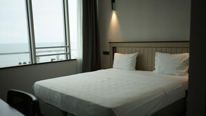 A neatly made bed in a hotel room with a view of the sea through large windows. - WEEN OTEL (Trabzon)