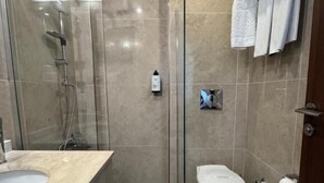 A modern bathroom with a glass-enclosed shower, a toilet, and a sink. - WEEN OTEL (Trabzon)