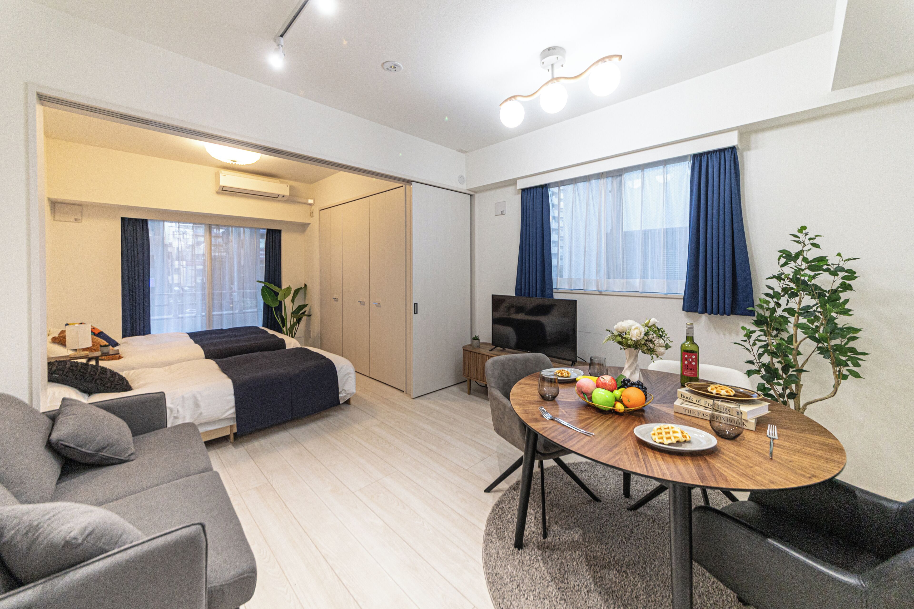A modern hotel room with a bed, a seating area with a table, and a TV.