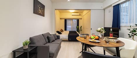 Una sala de estar moderna con un sofá, una mesa de comedor con un florero y un televisor.