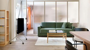 A modern living room with a green sofa, a wooden coffee table, a TV on a stand, and a bookshelf. - Kings Square 3BR by Daniel&Jacob's (København)
