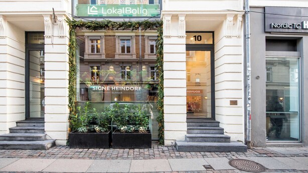 A building with a sign reading "LokalBolig" and a shop named "Stine Heindorf Clinique" with a staircase leading to the entrance. - Kings Square 3BR by Daniel&Jacob's (København)