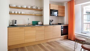 A modern kitchen with wooden cabinets, a countertop, and a window with orange curtains. - Kings Square 3BR by Daniel&Jacob's (København)