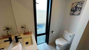 Et moderne badeværelse med et stort spejl, en hvid vask og et toilet.