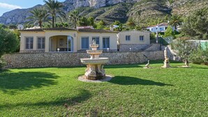 A property with a stone wall, a fountain, and a view of mountains.