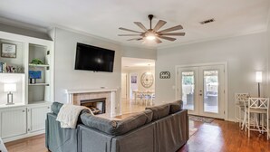 A living room with a gray sectional sofa, a flat-screen TV, a fireplace, and a ceiling fan. - Updated Retreat w/ Outdoor Space in Flowood! (Flowood)