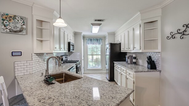A kitchen with white cabinets, a granite countertop, a stainless steel sink, and a black refrigerator. - Updated Retreat w/ Outdoor Space in Flowood! (Flowood)