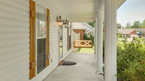 A covered porch with a swing, a wooden bench, and a door with a screen. - Updated Retreat w/ Outdoor Space in Flowood! (Flowood)