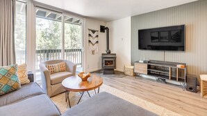 A modern living room with a sofa, armchair, coffee table, fireplace, TV, and wooden flooring. - Stroll to The Village: Year-Round Family Getaway (Mammoth Lakes)