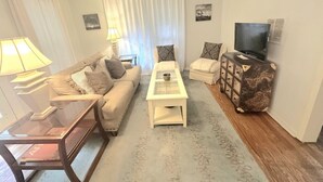 Ein Wohnzimmer mit einer Couch, einem Couchtisch, einem Fernseher und einem Beistelltisch.