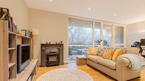 Een woonkamer met open haard, bank en televisie.