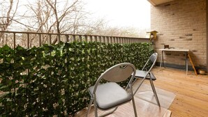 Een balkon met een metalen stoel, een tafeltje en een bakstenen muur.