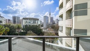 Un bâtiment moderne doté de balcons, un ciel dégagé et une tour qui se profile à l’horizon.