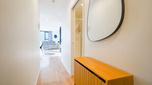 A hallway with a wooden console, a round mirror, and a staircase leading to a living area. - Stylish 2-Bedroom Apartment in Central Auckland (Auckland)